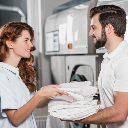 Photo illustrant le service de blanchisserie professionnelle avec 2 personnes s'échangeant du linge