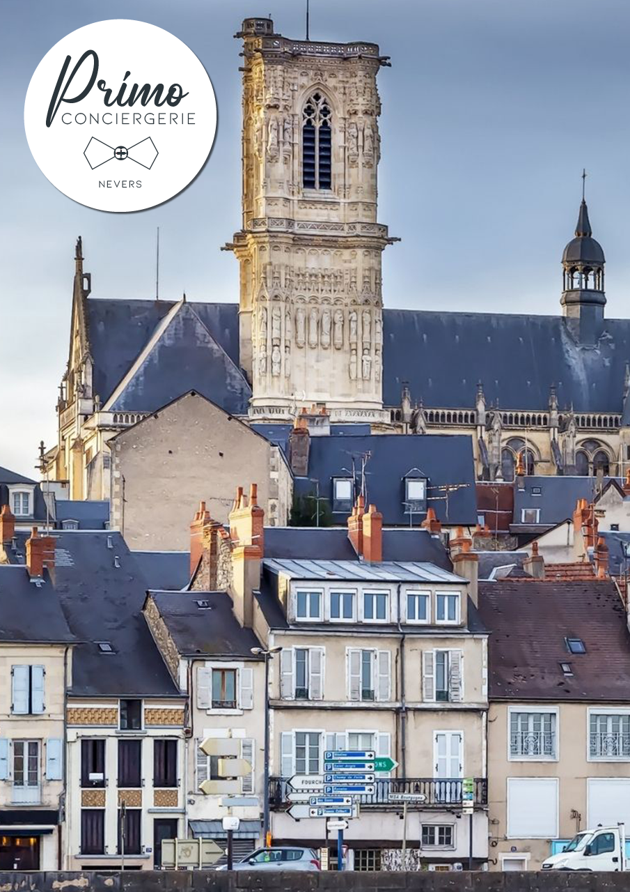 Vue de la cathédrale de Nevers avec des bâtiments historiques en avant-plan.