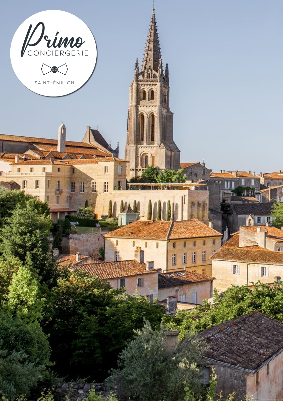 Vue sur l'église et les bâtiments anciens de Saint-Émilion, au milieu de la verdure.