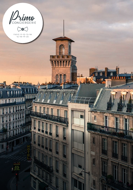 Vue sur les toits de Paris avec une tour architecturale au crépuscule.