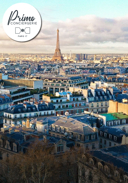 Vue aérienne sur les toits de Paris avec la Tour Eiffel au loin.