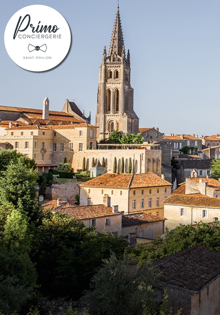 Vue sur l'église et les bâtiments anciens de Saint-Émilion, au milieu de la verdure.