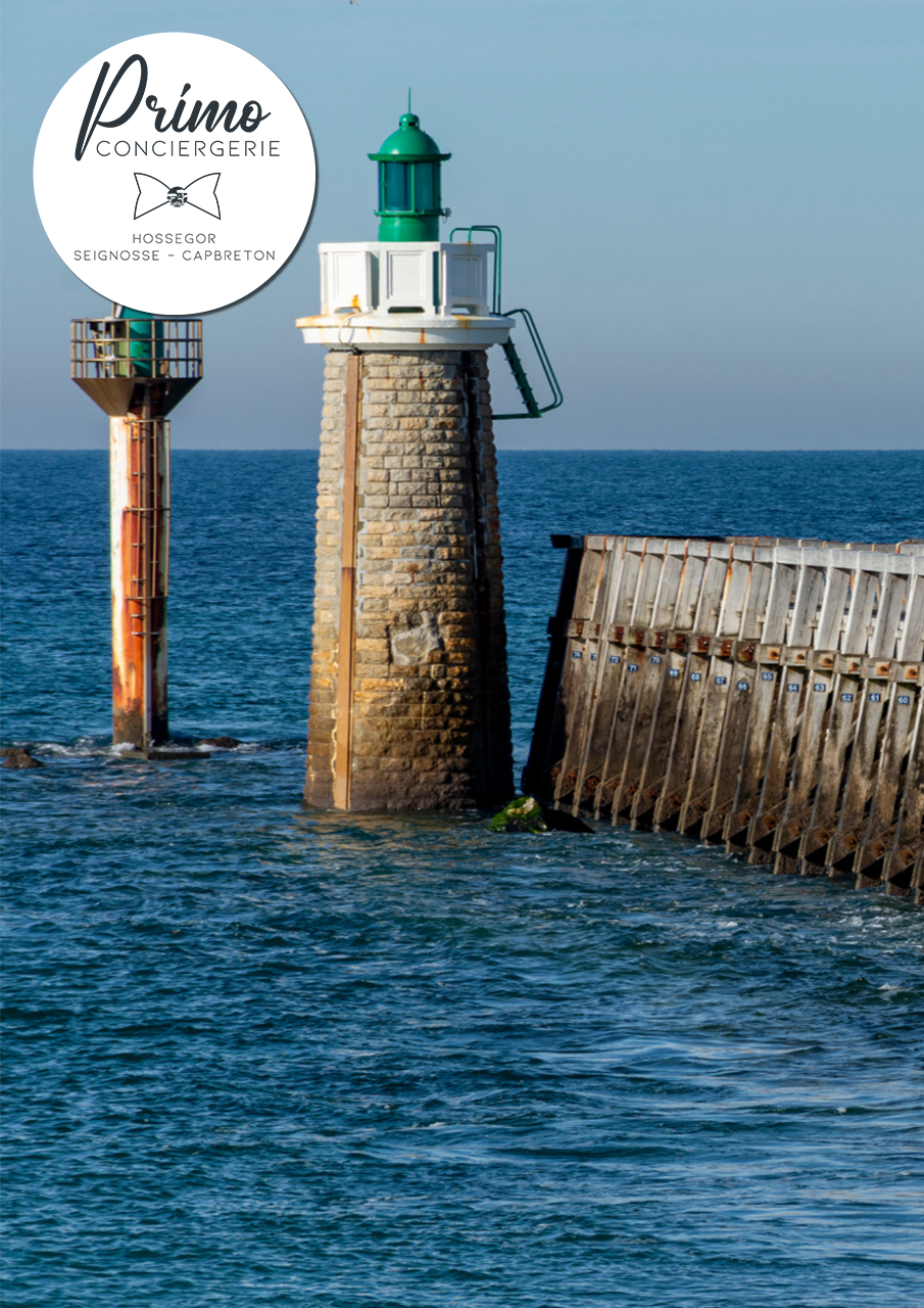 Phare de Capbreton avec une jetée en bois, capturée sous un ciel dégagé.